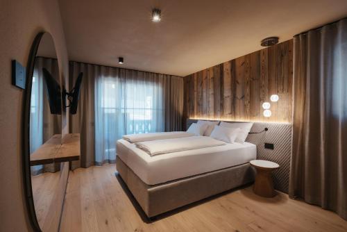 1 dormitorio con 1 cama grande y espejo en Pescosta Chalet Luxury Living, en San Vigilio Di Marebbe
