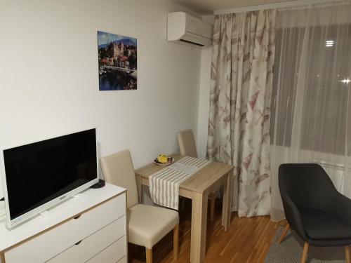 salon z telewizorem, stołem i krzesłem w obiekcie Nina apartman w mieście Donje Mladice