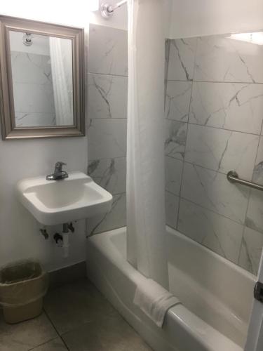 a bathroom with a sink and a tub and a mirror at A1A Travel Inn in Ormond Beach