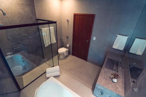 a bathroom with a tub and a toilet and a shower at Serravita Hotel in Piumhi
