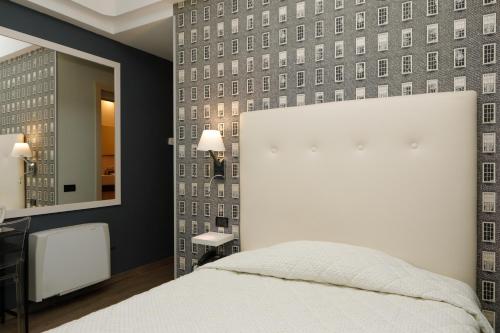 1 dormitorio con cama blanca y espejo en Hotel Lancaster, en Turín