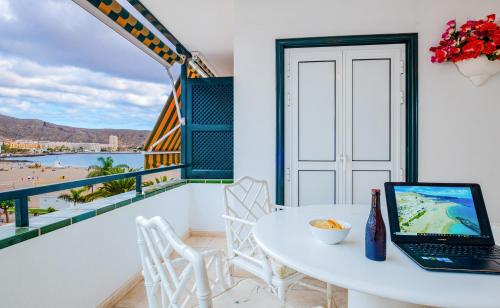 un balcon blanc avec une table et un ordinateur portable. dans l'établissement La Maricita Cristianos - Beach Front & Sea View, à Los Cristianos