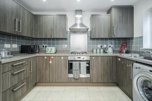 a kitchen with wooden cabinets and a stove top oven at Stunning 3BR house in Basildon in Basildon