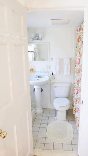 a white bathroom with a toilet and a sink at An English Garden in Dennis Port