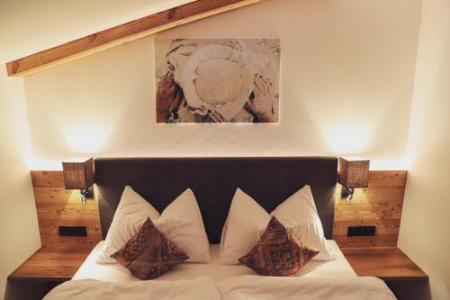 ein Schlafzimmer mit einem Bett mit Kissen und einem Gemälde an der Wand in der Unterkunft Mocking Ferienappartements in Kitzbühel