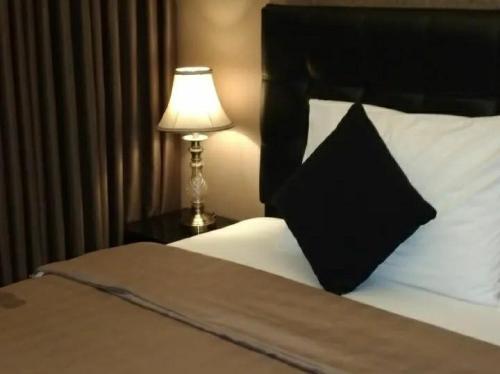 um quarto com uma cama com uma almofada preta e um candeeiro em Apartement Grand Asia Afrika Bandung by House Of Tofi em Bandung