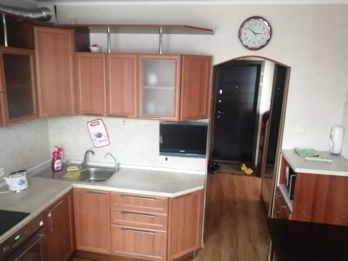 a kitchen with wooden cabinets and a black refrigerator at "СКомфортом" однокомнатная квартира на Проспекте Мира 375 in Yuzhno-Sakhalinsk