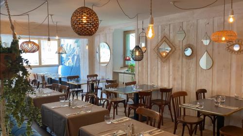 un restaurante con mesas, sillas y luces colgantes en Logis La Chaumière Saint-Maurice, en Thorens-Glières