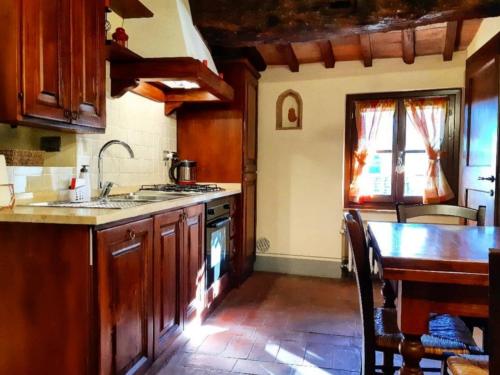 a kitchen with wooden cabinets and a table and a sink at Le Torri San Gimignano Apartments in San Gimignano
