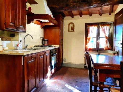 kuchnia z drewnianymi szafkami, stołem i zlewem w obiekcie Le Torri San Gimignano Apartments w mieście San Gimignano