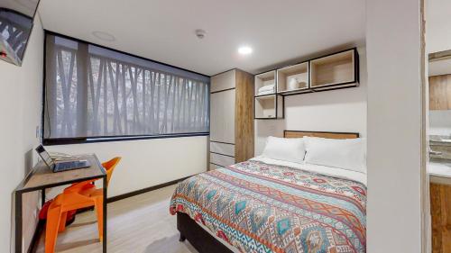 a bedroom with a bed and a desk and a window at Terrazas in Bogotá