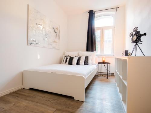 - un lit blanc dans une chambre blanche dotée d'une fenêtre dans l'établissement EUPHORAS - Geschmackvolles Apartment in Hannover, à Hanovre