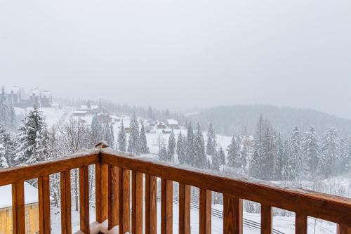 a view of a snow covered mountain from a deck at Rich OAK - готель з відкритим панорамний басейном in Yablunytsya