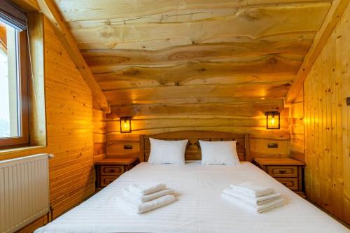 a bed in a wooden room with towels on it at Rich OAK - готель з відкритим панорамний басейном in Yablunytsya