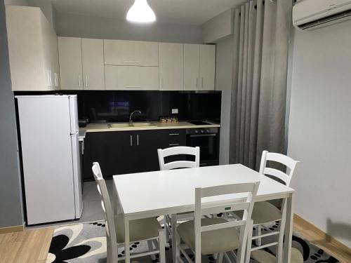 a kitchen with a white table and chairs and a refrigerator at Noel's Home in Korçë