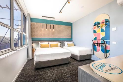 a bedroom with two beds and a surfboard on the wall at Royal Hotel by Nightcap Social in Melbourne