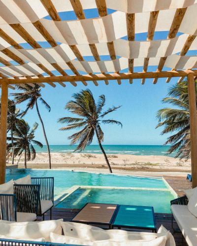 a swimming pool with palm trees and the beach at Pousada Kiriri in Itarema