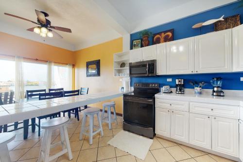 a kitchen with white cabinets and a bar with stools at Suite F201 @ Mara Laguna in San Pedro