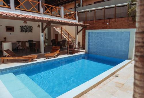 uma grande piscina com cadeiras e uma mesa em Vila Moana Jeri em Jericoacoara