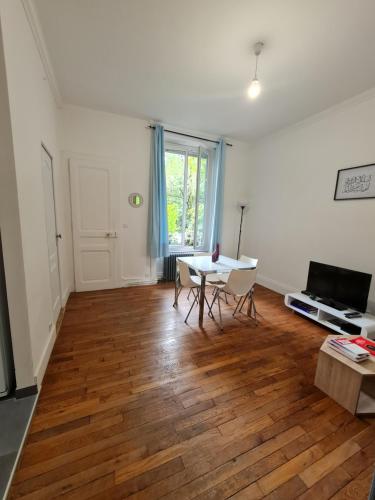 a living room with a wooden floor and a table at Appartement de charme avec parking et terrasse in Besançon