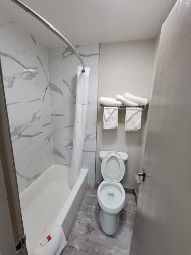 a bathroom with a toilet and a tub and a sink at Days Inn by Wyndham Ruidoso Downs in Ruidoso Downs