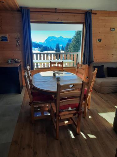 une table et des chaises dans une pièce avec une grande fenêtre dans l'établissement Les Terrasses Du Mont Blanc, à Praz de Lys - Sommand