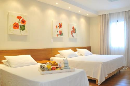 a hotel room with two beds with a tray of fruit on one of them at Hotel Recanto Bela Vista in Águas de Lindóia