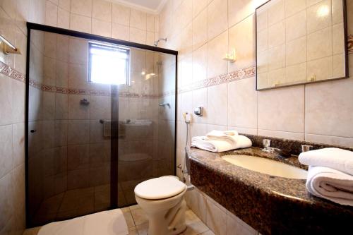 a bathroom with a toilet and a sink and a shower at Hotel Recanto Bela Vista in Águas de Lindóia