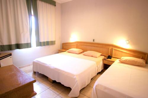 a hotel room with two beds and a window at Hotel Recanto Bela Vista in Águas de Lindóia