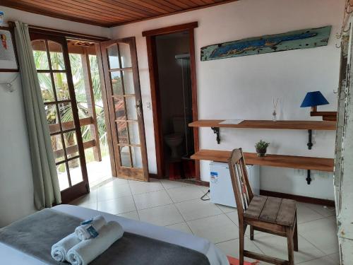 a bedroom with a bed and a desk and a chair at Pousada Icthus in Cabo Frio
