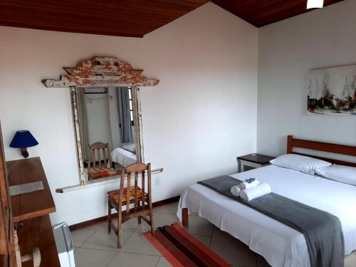 a bedroom with a bed and a mirror and a chair at Pousada Icthus in Cabo Frio