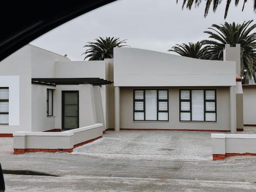 a white house with palm trees in the background at Avodation in Walvis Bay