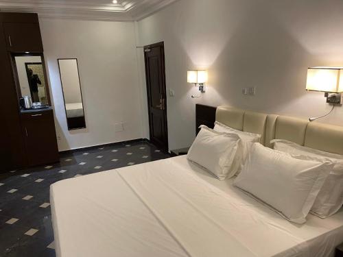 a bedroom with a white bed with two pillows at HOTEL LES ARCADES in Abomey-Calavi