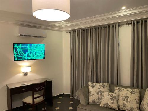 a living room with a couch and a desk and a television at HOTEL LES ARCADES in Abomey-Calavi