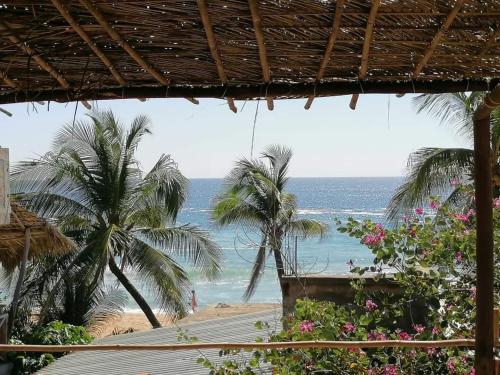 een uitzicht op een strand met palmbomen en de oceaan bij Posada Casa San Agus in San Agustinillo
