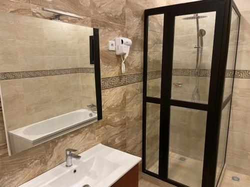 a bathroom with a sink and a shower and a mirror at HOTEL LES ARCADES in Abomey-Calavi