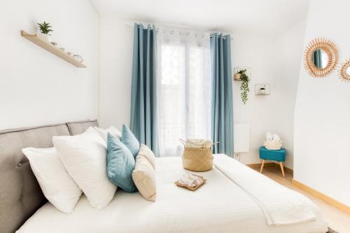 Schlafzimmer mit einem Bett mit weißen und blauen Kissen in der Unterkunft Grand Line - Parking- Métro 5 - Easy Check-in - Netflix - Disney Plus in Pantin