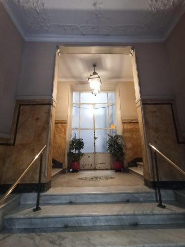 a hallway with stairs and a door with two plants at Paradise Rooms - Brignole Station in Genova