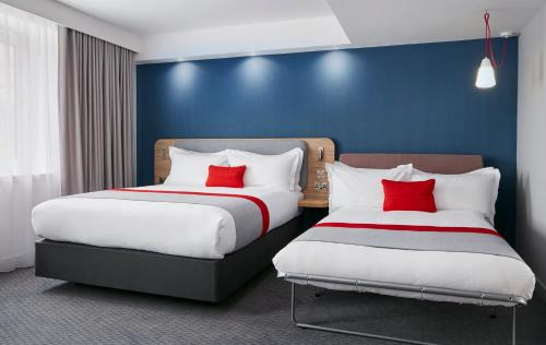 two beds in a room with blue walls and red pillows at Holiday Inn Express Dublin City Centre by IHG in Dublin