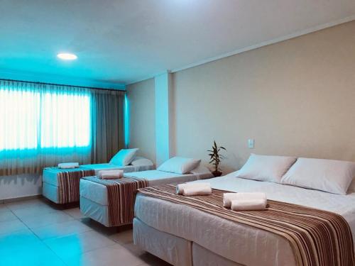 una habitación de hotel con 2 camas y una silla en Hotel Castelo Branco en Foz de Iguazú