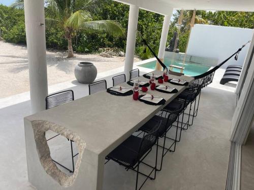 a dining table and chairs on a patio with a pool at Casa Almea Sisal in Sisal