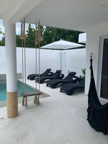 a group of chairs and an umbrella next to a pool at Casa Almea Sisal in Sisal