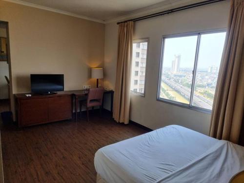 um quarto de hotel com uma cama, uma secretária e uma janela em Hunian dekat T I Ancol, pintu Toll, Itc Mangga dua em Jakarta