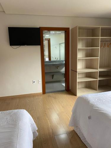 a bedroom with a bed and a bathroom with a sink at Katuny Pousada e Eventos in São Domingos do Prata
