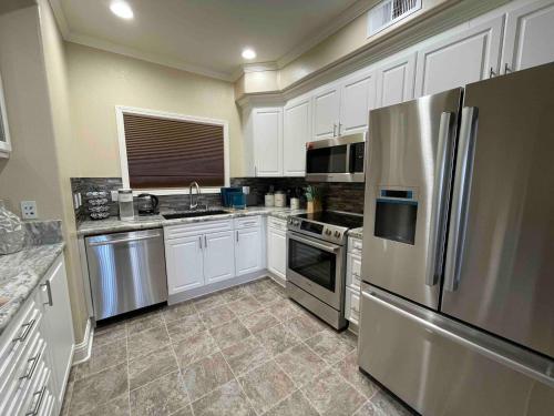 a kitchen with white cabinets and a stainless steel refrigerator at Balmoral in Santa Clara