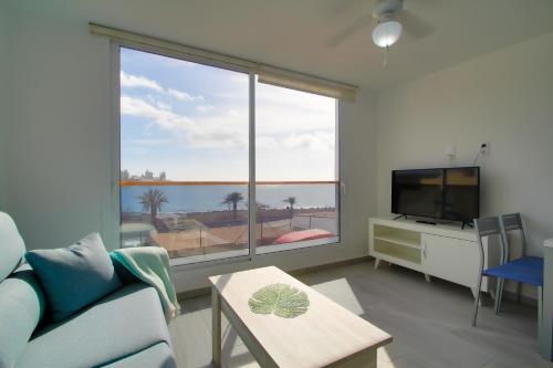 salon z kanapą i dużym oknem w obiekcie Neues Apartment am Strand w mieście Arguineguín