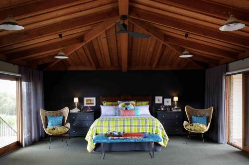 a bedroom with a bed and two chairs at Shaws Road Winery B&B in Arthurs Creek