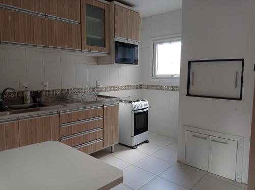 cocina con armarios de madera y horno de fogón blanco en Amplo e Central Apartamento 3 Quartos, en Gramado