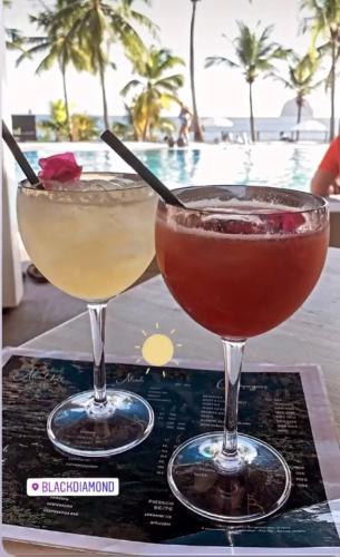 two cocktails sitting on top of a table near a pool at Lady laying in Le Diamant