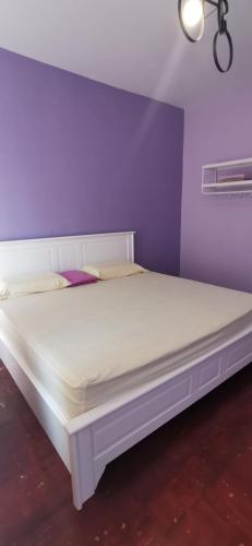 a white bed in a room with a purple wall at BayView Villas Condo - Premium Unit in Port Dickson